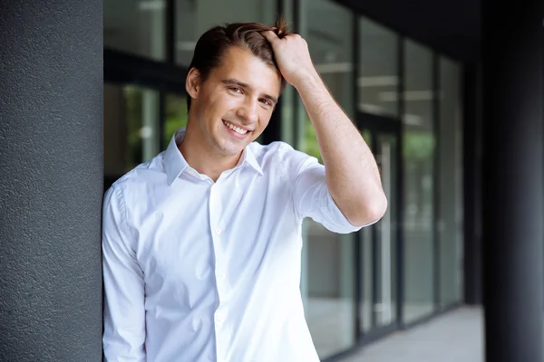 Fröhlich selbstbewusster junger Geschäftsmann steht und lächelt — Stockfoto