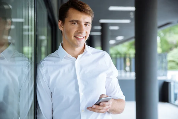 Sonriente joven hombre de negocios utilizando el teléfono inteligente — Foto de Stock