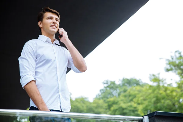 Mosolygó sikeres fiatal üzletember mobiltelefonon beszél — Stock Fotó
