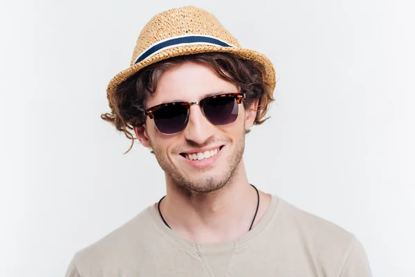 Closeup of cheerful young man in hat and sunglasses smiling — Stock Photo, Image