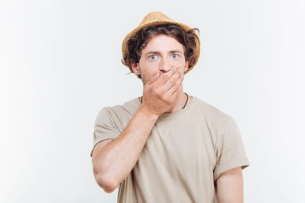 Pohledný mladý muž v klobouku pokrývá ústa ručně — Stock fotografie