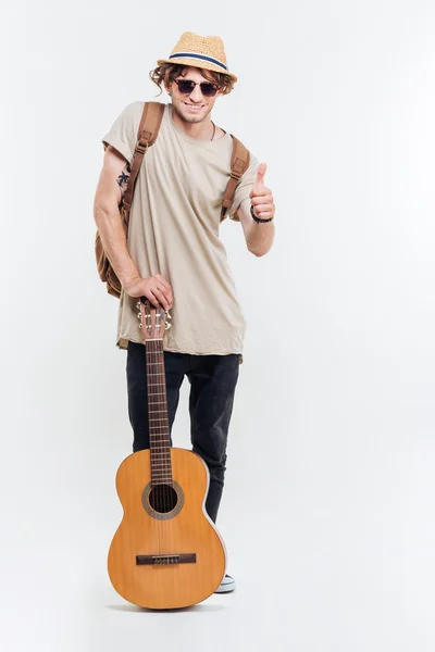 Hombre con gafas de sol sosteniendo la guitarra y mostrando los pulgares hacia arriba — Foto de Stock