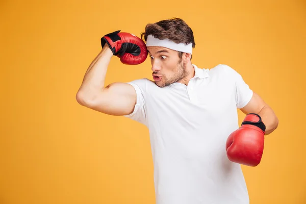 Boxeador de hombre cómico sorprendido con guantes rojos mostrando sus bíceps —  Fotos de Stock