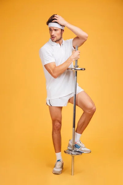 Attractive young man athlete standig and posing with barbell — Stock Photo, Image