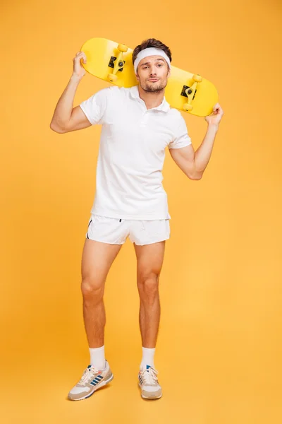 Guapo joven patinador sosteniendo un monopatín sobre sus hombros —  Fotos de Stock