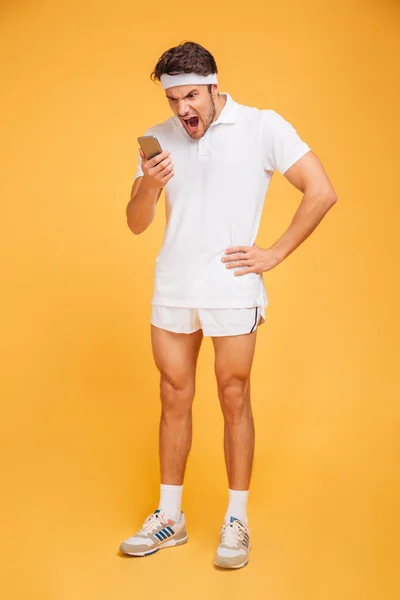 Enojado joven deportista gritando en el teléfono móvil — Foto de Stock