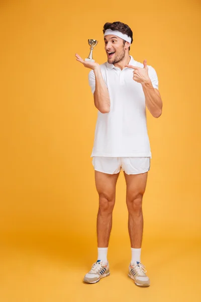 Fröhlicher Mann Sportler hält Pokal in der Hand und zeigt darauf — Stockfoto