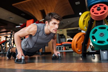 Fitness man working out and doing push-ups in gym clipart