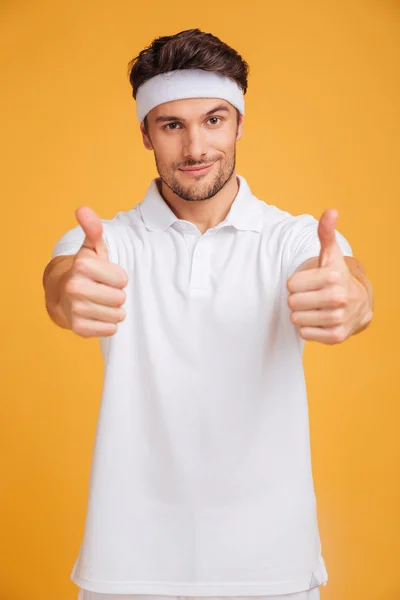 Confident young man athlete showing thumbs up with both hands — Stock Photo, Image