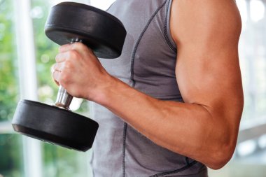 Atletik genç adam atlet spor salonunda dambıl kullanarak eğitim