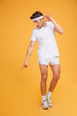 Şaşkın genç sporcu ayakta ve aşağı işaret