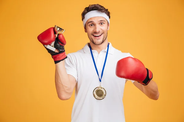 Bokser człowiek w czerwone rękawiczki i medal trzyma trofeum Pucharu — Zdjęcie stockowe