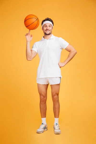 Sonriente jugador de baloncesto haciendo girar la pelota en su dedo — Foto de Stock