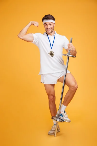 Mosolygó fiatal fitness ember mutatja bicepsz és gazdaság súlyzó — Stock Fotó
