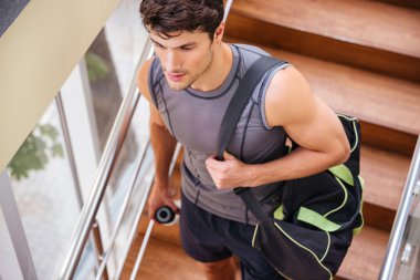 Spor salonunda merdivenlerde yürüyen çanta ile Fitness adam