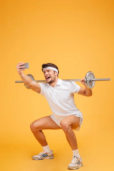 Sportsman utbildning med skivstång och pratar Selfie med mobiltelefon — Stockfoto