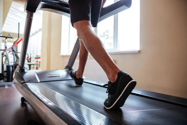Lábak a fiatal fitness ember fut a futópadon a tornateremben — Stock Fotó