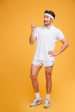 Ayakta ve uzağa işaret neşeli yakışıklı genç fitness adam