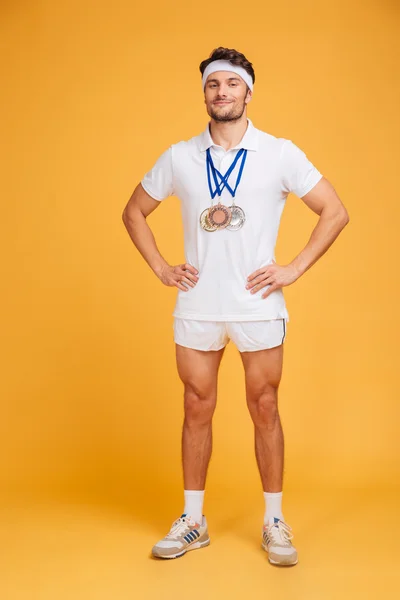 Üç madalya ile kendinden emin gülümseyen sporcu tam uzunlukta — Stok fotoğraf