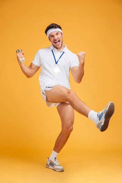 Desportista alegre com medalha de ouro e taça de troféu celebrando a vitória — Fotografia de Stock