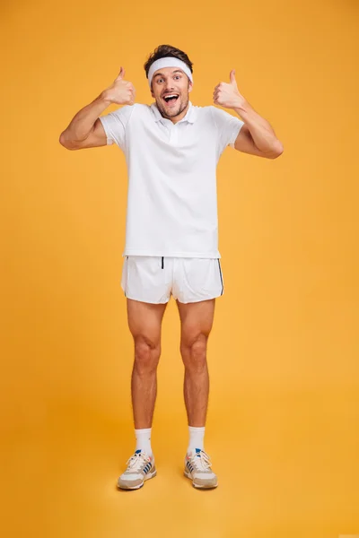 Cheerful excited young sportsman standing and showing thumbs up — Stock Photo, Image
