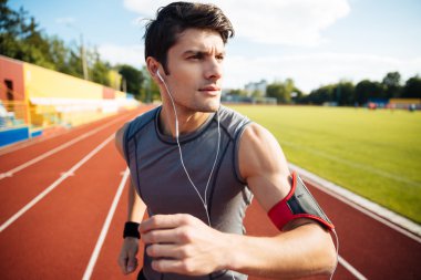 Earphones ile çalışan bir spor adam portresi kapatın