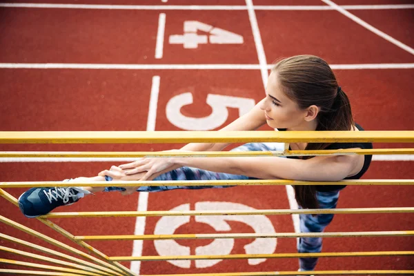 Retrato de uma mulher esportiva esticando as pernas no estádio ao ar livre — Fotografia de Stock