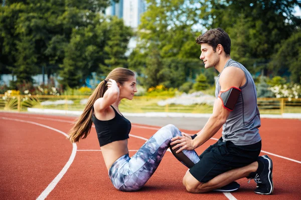 Young beautiful couple doing exercises at the stadium — Stock Photo, Image