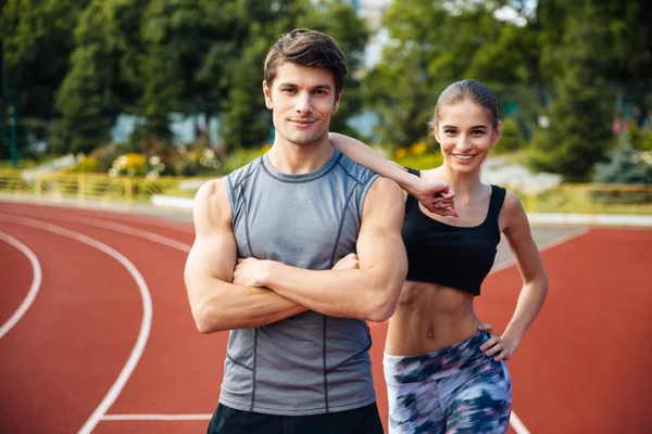 Young man and woman standing on athletics race track — Stock Photo, Image