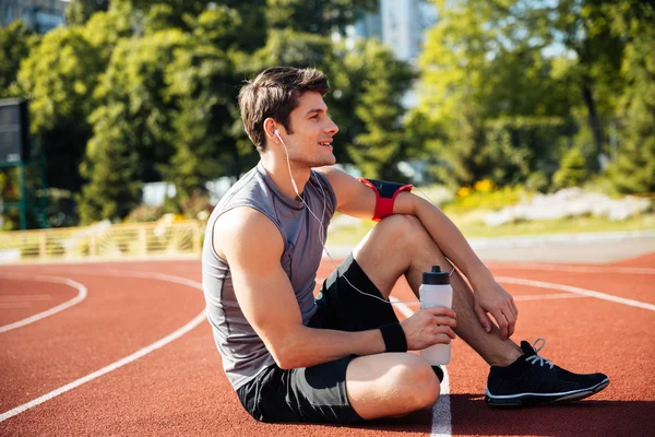 Jovem atleta bonito descansando no estádio — Fotografia de Stock