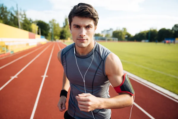 Retrato de cerca de un deportista corriendo con auriculares — Foto de Stock