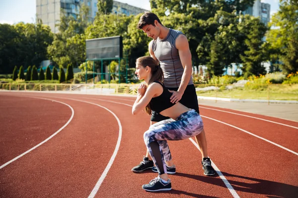 Youngl couple doing sports exercises at the stadium — Stock Photo, Image