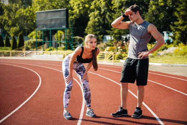 Tired fitness couple of runners at the stadium — Stock Photo, Image