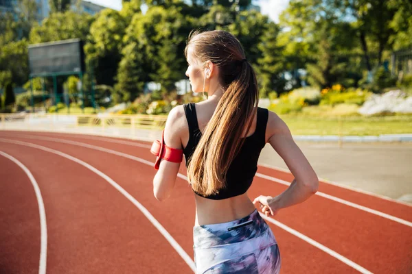 Bakifrån av en kvinnlig löpare med mobiltelefon — Stockfoto