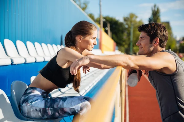 Giovane coppia in piedi e parlando sul campo di atletica leggera — Foto Stock