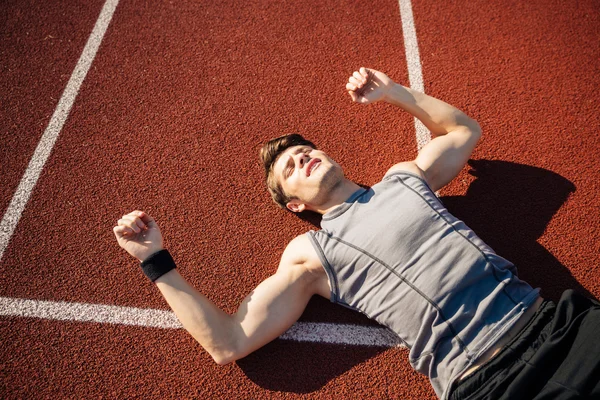 Фітнес молодий чоловік лежить на біговій доріжці після важкого тренування — стокове фото