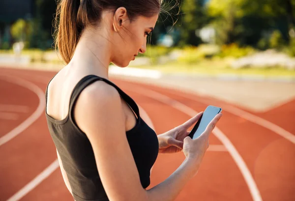 Zijaanzicht van de vrouw rust na run en het gebruik van smartphone — Stockfoto