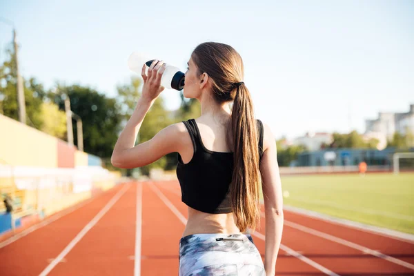 Young female athlete drinking from water bottle after workout outdoors — Stock Photo, Image