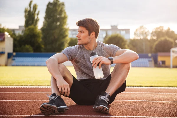 Mladý pohledný muž sportovec odpočívá s láhev s vodou — Stock fotografie