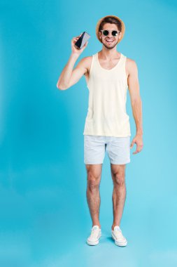 Mutlu genç adam ayakta ve elinde boş perde hareket eden telefon