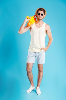 Ciddi genç mamn ayakta ve su tabancası ile poz