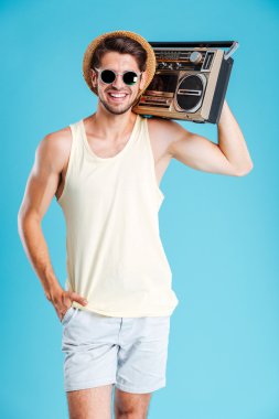 Şapka ve güneş gözlüğü boombox holding neşeli çekici bir genç adam
