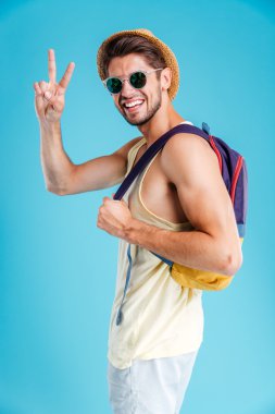 Barış işareti gösterilen sırt çantası ile gülümseyen genç adam