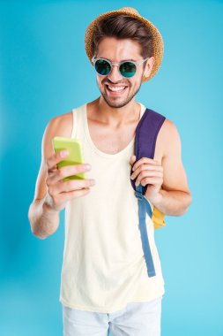 Cep telefonu kullaranarak sırt çantası ile neşeli genç adam