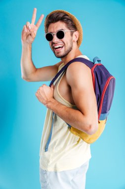 Sırt çantası ve gösteren barış işareti holding neşeli genç adam
