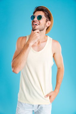 Şapka ve güneş gözlüğü ararken neşeli genç adam