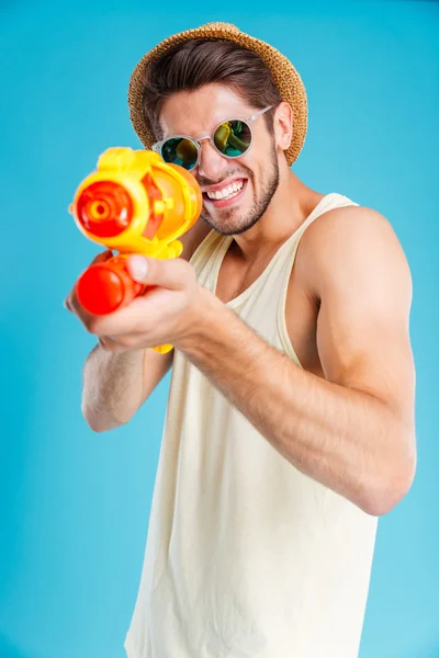 Cheerful young man having fun using water gun — Stock Photo, Image