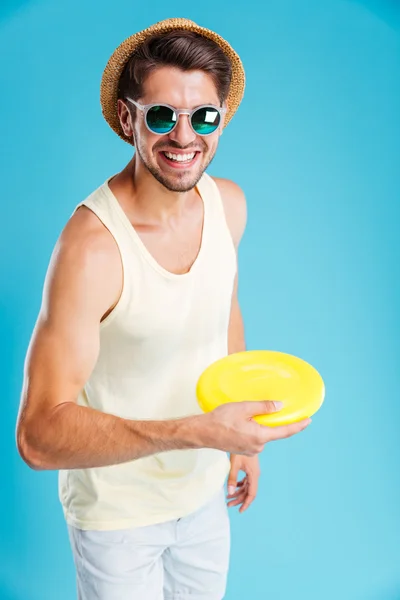 Sorrindo homem de chapéu e óculos de sol brincando com disco frisbee — Fotografia de Stock
