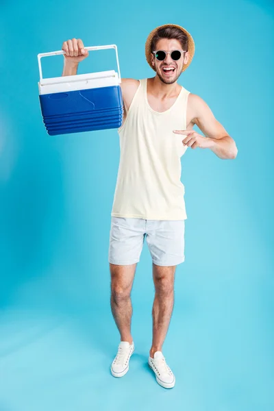 Feliz joven sosteniendo y señalando en bolsa más fresca — Foto de Stock