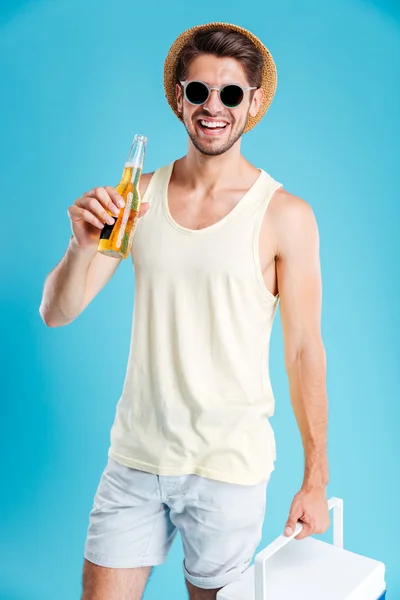 Счастливый молодой человек с крутой сумкой стоит и пьет пиво — стоковое фото